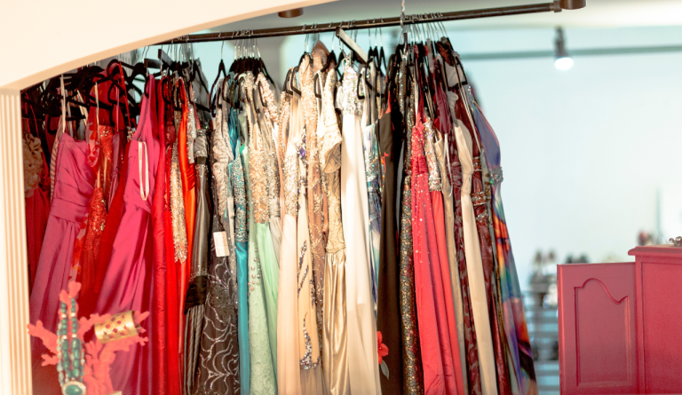 Abiti da cerimonia eleganti e colorati appesi su una rastrelliera in un atelier di moda